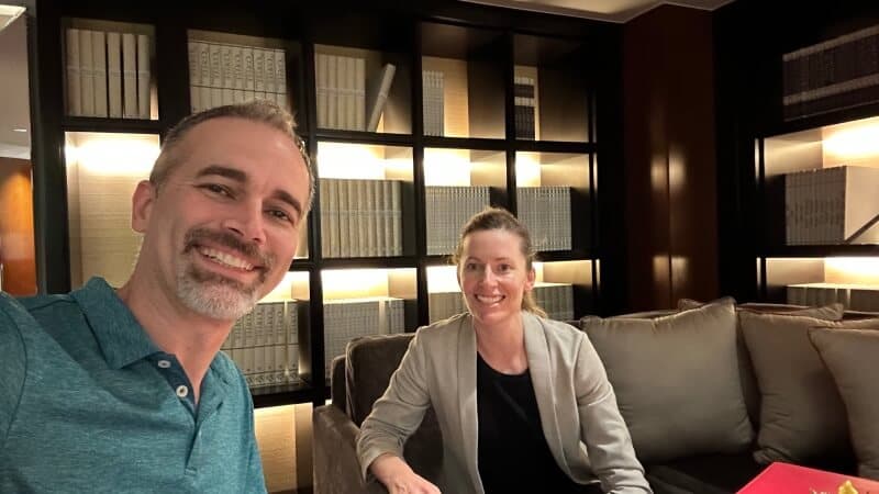 Isaac and Meryl smiling in a hotel lounge in front of lit bookshelves